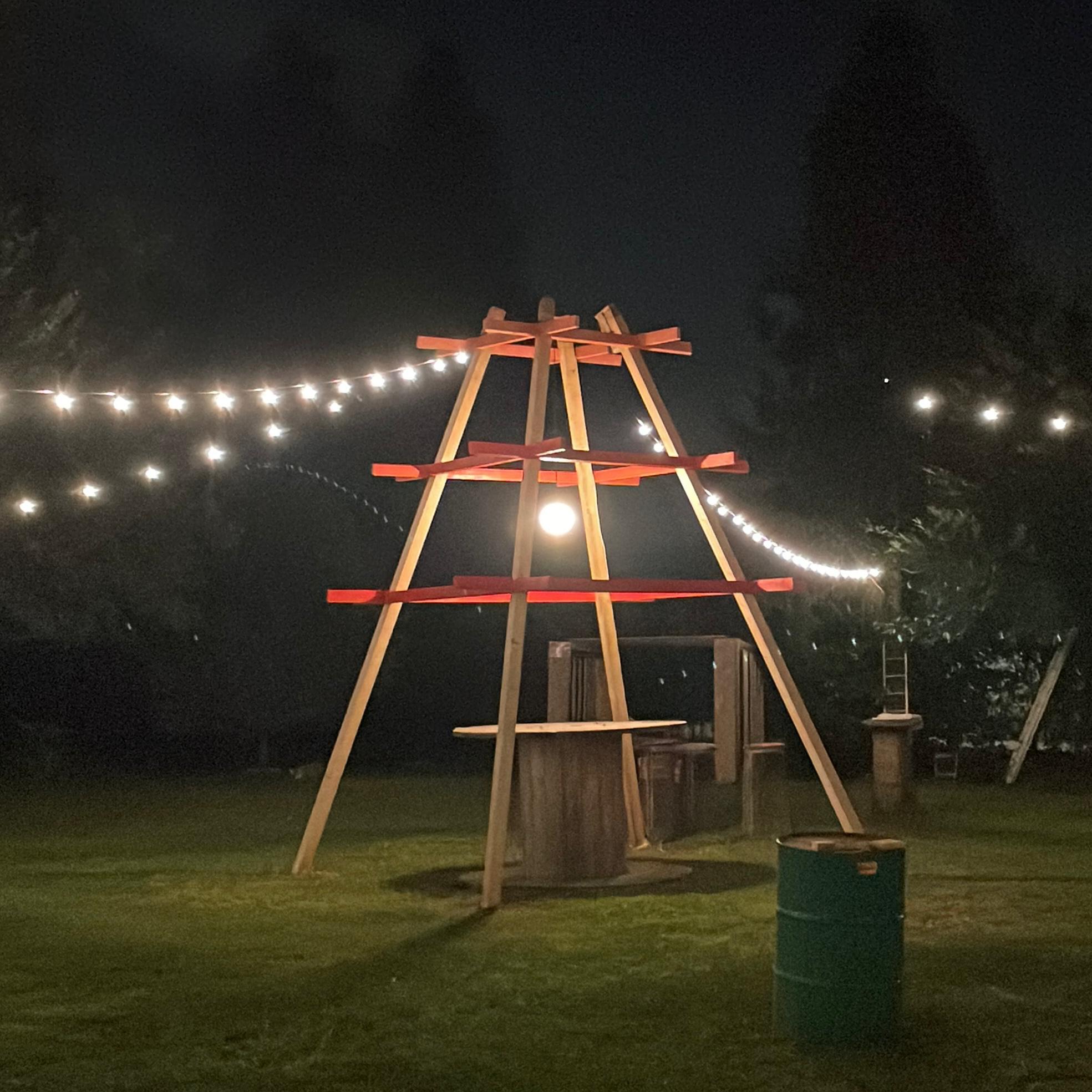 Totem in legno illuminato da fili di luci nel giardino di notte